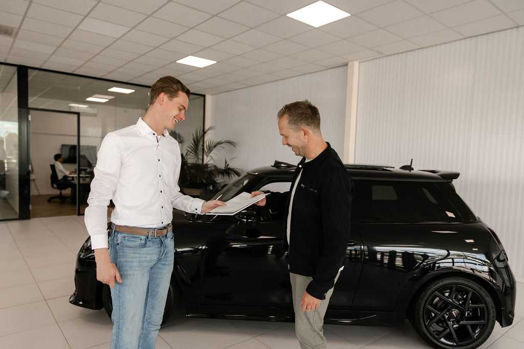 Autoverkoper overhandigt contract aan klant